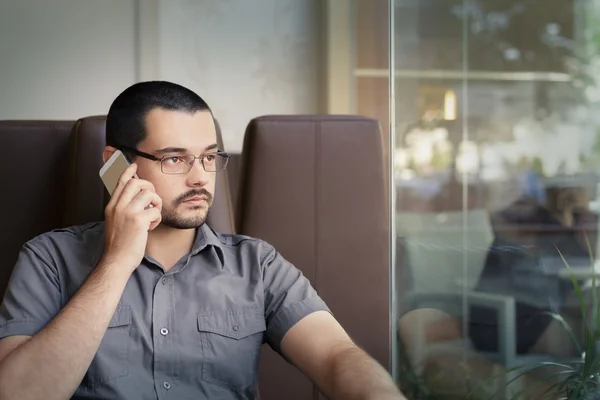 Молодий чоловік в окулярах розмовляє по телефону — стокове фото