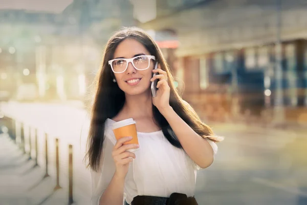 Mujer joven con taza de café en el teléfono en la ciudad —  Fotos de Stock