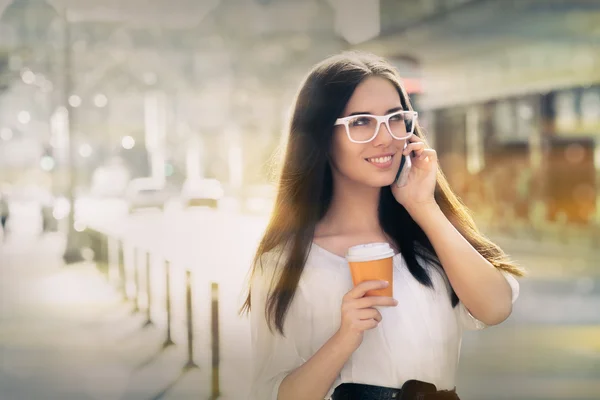 Jeune femme avec tasse de café au téléphone dans la ville — Photo