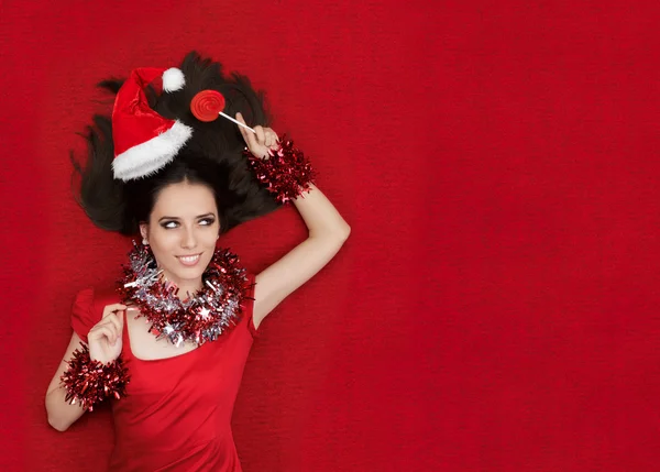 Feliz Navidad chica sosteniendo una piruleta sobre fondo rojo — Foto de Stock