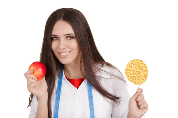 Nutrizionista in possesso di una mela e una grande caramella — Foto Stock
