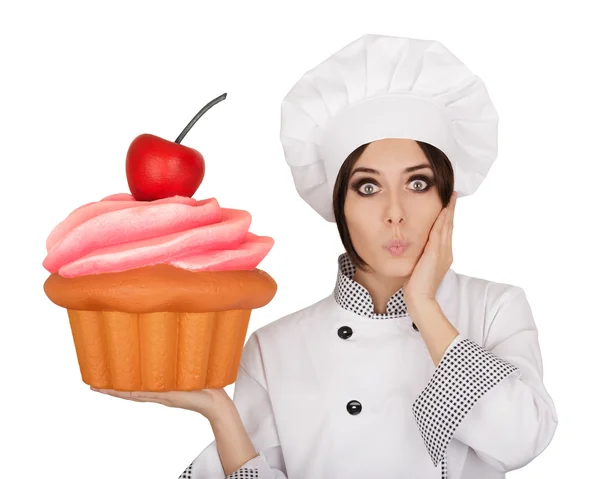 Mujer asombrada pastelera sosteniendo enorme magdalena —  Fotos de Stock