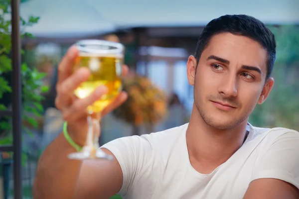 Jeune homme levant un verre dans un bar — Photo