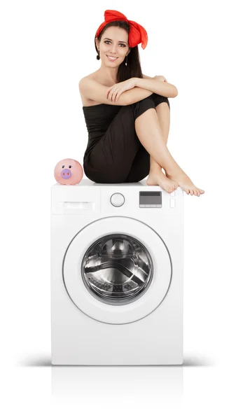 Девушка с копилкой свиньи на стиральной машине — стоковое фото