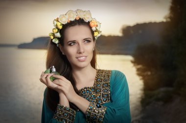 Parfüm şişesi güneş ışığı altında tutan genç kadın