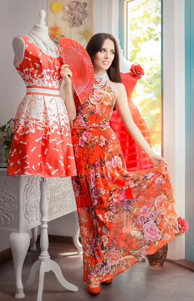 Vrouw in lange rode bloemen jurk in Fashion Store — Stockfoto
