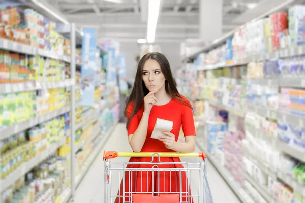 Nieuwsgierig vrouw in de supermarkt met het winkelen lijst — Stockfoto