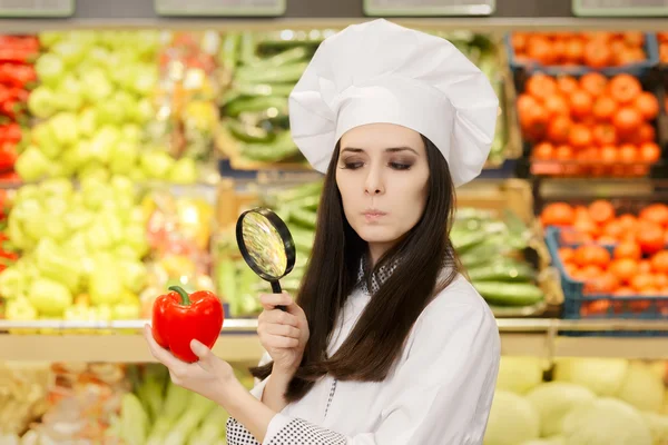 Betrokken Lady Chef-kok inspectie van groenten met Vergrootglas — Stockfoto