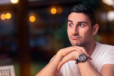 Surprised Young Man Sitting in a Restaurant