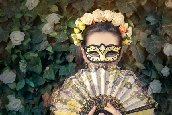 Belle femme avec couronne florale, masque et ventilateur — Photo