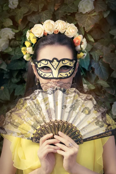 Hermosa mujer con corona floral, máscara y abanico — Foto de Stock