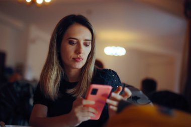 Bir restoranda hoş olmayan bir telefon alan bir kadın.