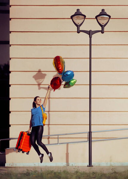 Путешествующая женщина с чемоданом летит прочь с гелиевыми шариками