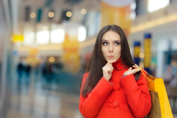 Menina curiosa em um casaco vermelho Compras em um shopping — Fotografia de Stock