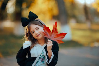 Moda kıyafetli küçük kız elinde bir akçaağaç yaprağı tutuyor