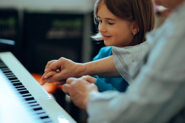Küçük kız müzik öğretmeninden piyano çalmayı öğreniyor.