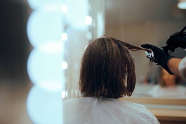 Kuaför müşterisinin saçına saç boyası sürüyor.