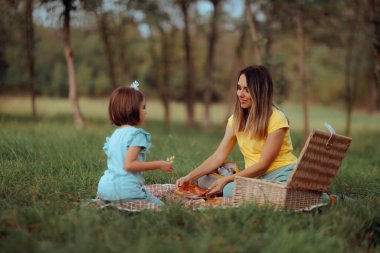 Anne ve küçük kız doğada piknik yapıyorlar.