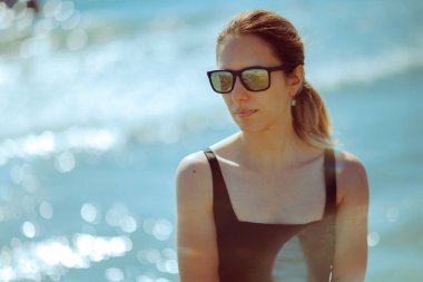 Deniz kenarında tatilde aynalı güneş gözlüğü takan kadın.