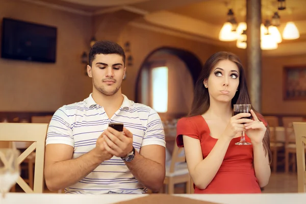 Aburrido chica en una cita con su novio adicto a su teléfono inteligente —  Fotos de Stock