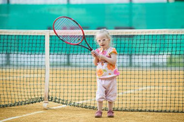 Down sendromlu güzel bir kız tenis oynuyor.