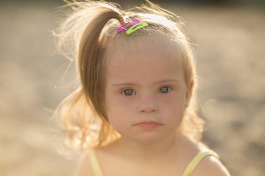 Down sendromlu bir kız sahilde sürünüyor.