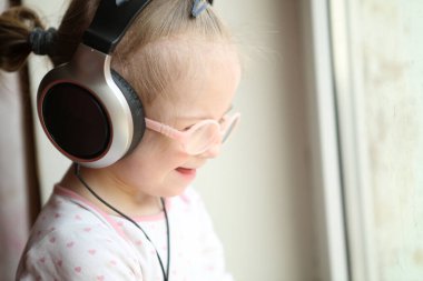 Down sendromlu güzel bir kız kulaklıkla müzik dinliyor.