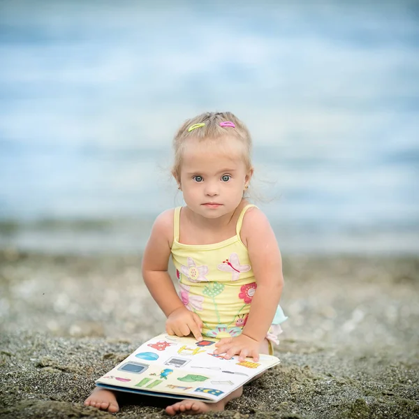 Menina Com Síndrome Olhar Para Fotos Livro Praia — Fotografia de Stock