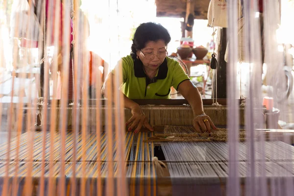 Mulher usando tear tradicional para tecer o tecido tailandês — Fotografia de Stock