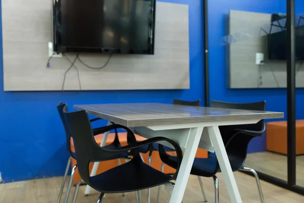 Black chair and wooden table in meeting room — Stock Photo, Image