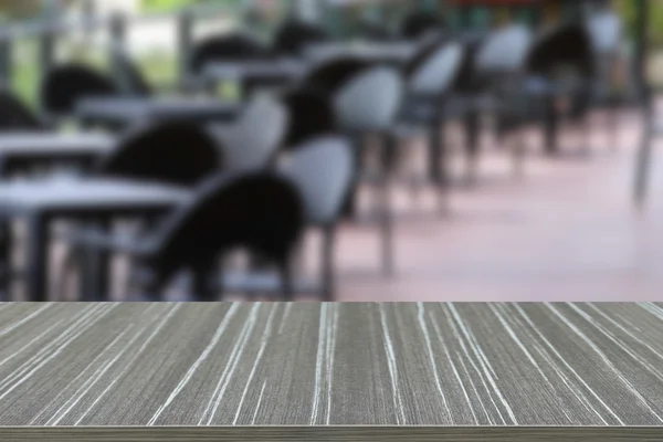 empty wooden table with black rattan table and chair on the terr