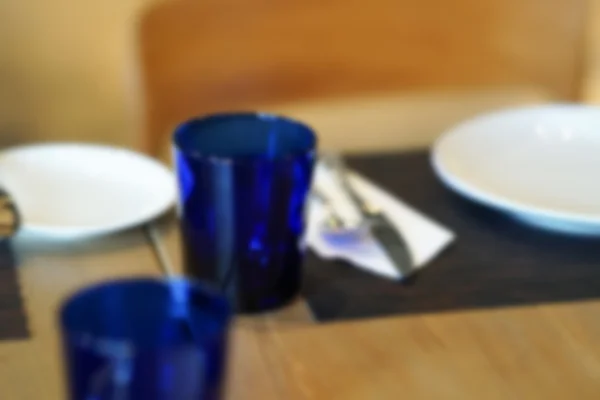 Skål, sked, gaffel och blå glas på träbord, oskärpa och defoc — Stockfoto