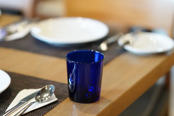 Skål, sked, gaffel och blått glas på träbord — Stockfoto