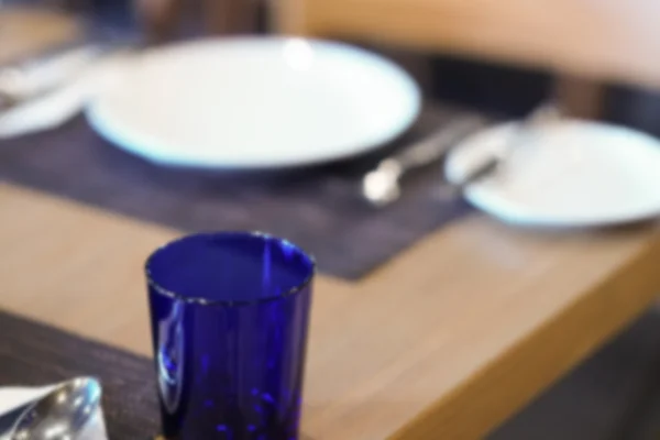 Skål, sked, gaffel och blå glas på träbord, oskärpa och defoc — Stockfoto