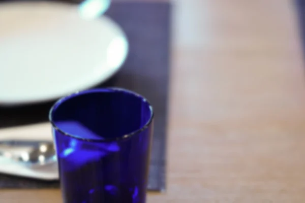 木製のテーブル、ぼかし、defoc 皿、スプーン、フォーク、ブルーのガラス — ストック写真