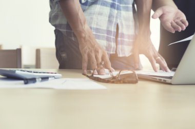 Hesap makinesi, iş belgesi ve bilgisayar notuyla çalışan adamlar