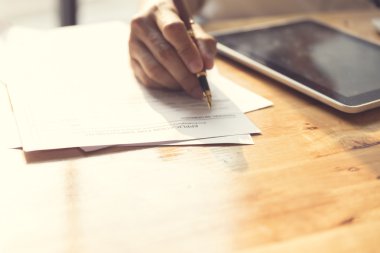 Adamın elini ahşap masa tablete ile başvuru formu imzalama