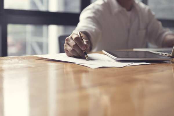 man 's hand working with laptop computer and business document
