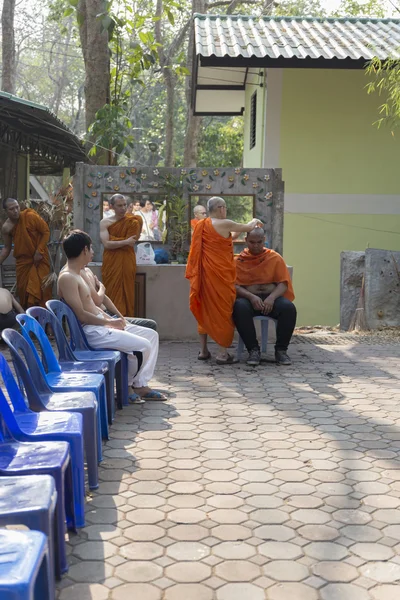 Монах бреет волосы человека перед церемонией рукоположения буддийских монахов — стоковое фото