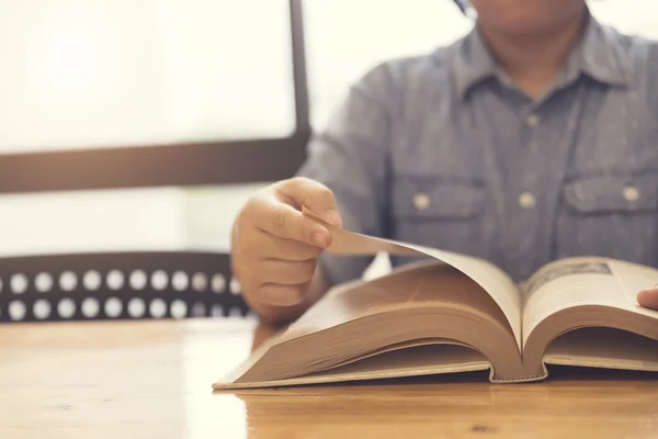 woman\'s hand reading book on wooden table