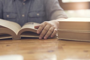 kadın eli ahşap masa kitap okuma