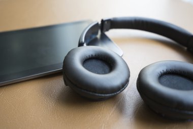 kulaklık ve kahverengi deri yastık üzerinde dijital tablet