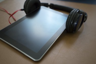 kulaklık ve kahverengi deri yastık üzerinde dijital tablet