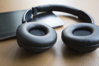 kulaklık ve kahverengi deri yastık üzerinde dijital tablet