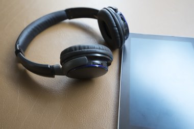 kulaklık ve kahverengi deri yastık üzerinde dijital tablet