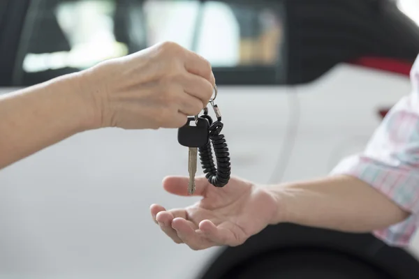 La mano de la gente da y consigue la llave del coche con el fondo del coche — Foto de Stock