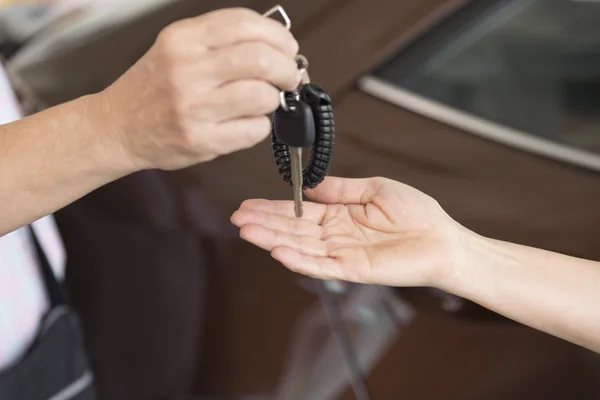 La mano de la gente da y consigue la llave del coche con el fondo del coche — Foto de Stock