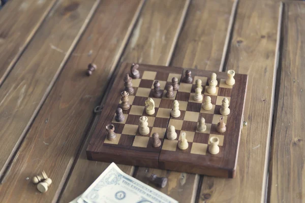 pawn, chessboard game and banknote on wooden table, vintage tone