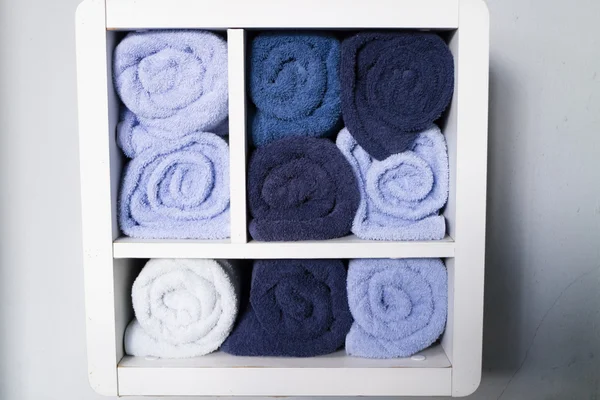 Rolling blue towel on white shelf — Stock Photo, Image