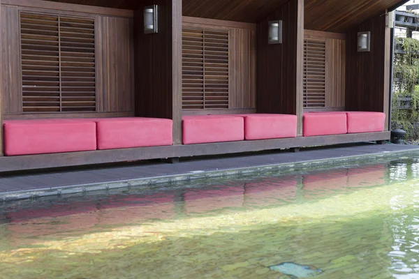 Cojín rojo en asiento de madera junto a la piscina — Foto de Stock
